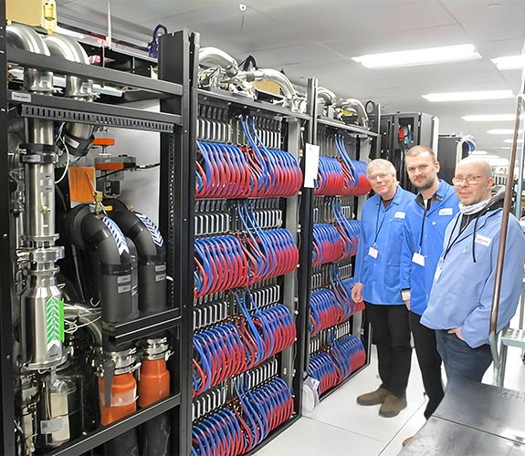 Three men standing in front of a supercomputer.