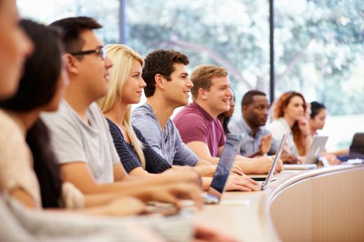 A row of smiling students in an auditorium. 