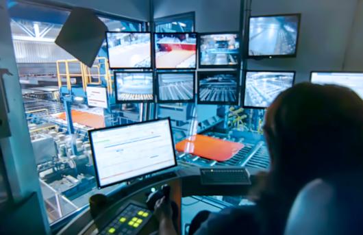 Personnell watching computer monitors in an industrial factory or plant setting. 