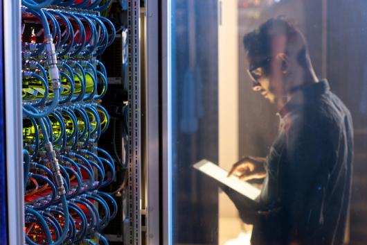 An IT person cheking the cables of a supercomputer